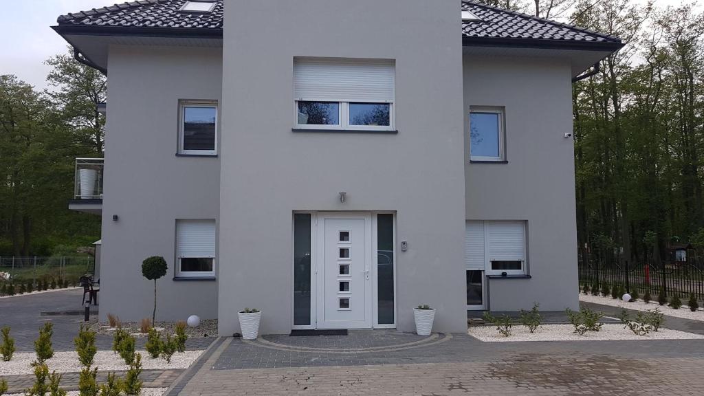 a white house with a white door and some plants at Apartamenty u Tatiany in Międzywodzie