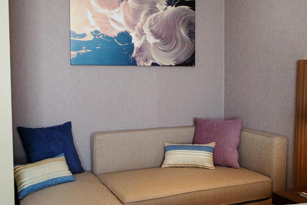 a couch with two pillows and a painting on the wall at Марциаль in Tyumen