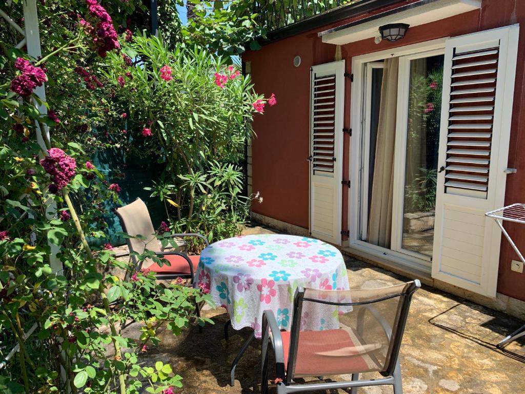 a table and chairs in a garden with flowers at Ap.Galerija Istok-Zapad 2 - "Very cozy" in Rovinj