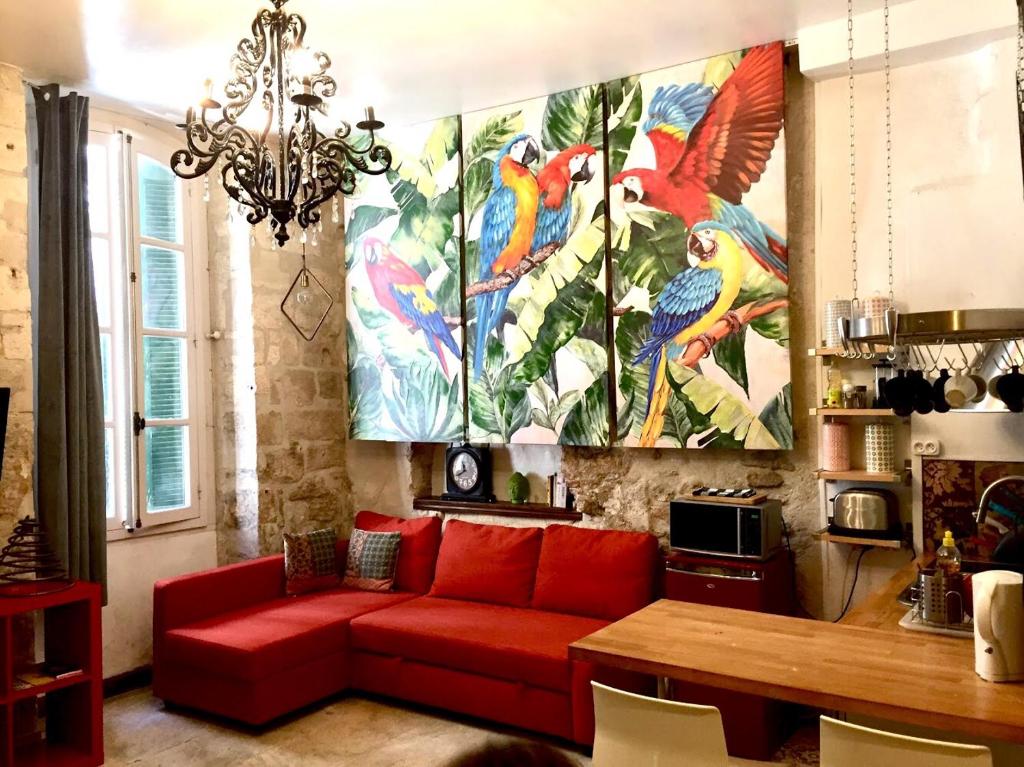 un salon avec un canapé rouge et un grand tableau dans l'établissement Appartements La Croix, à Avignon