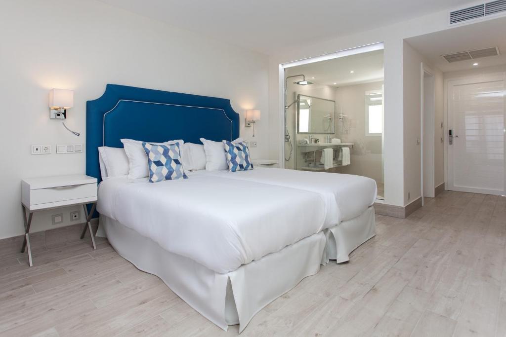 a large white bedroom with a large bed and a mirror at Hotel Boutique TAO Caleta Mar in Corralejo