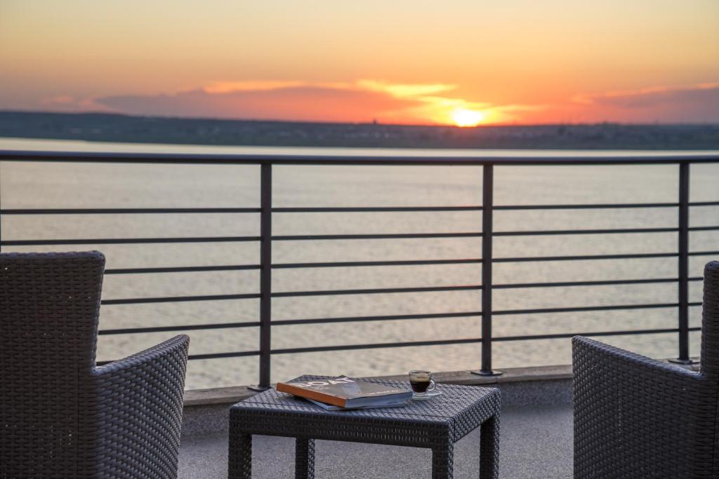 a table and chairs on a balcony with the sunset at Lake Boutique Apartments & Rooms in Mamaia