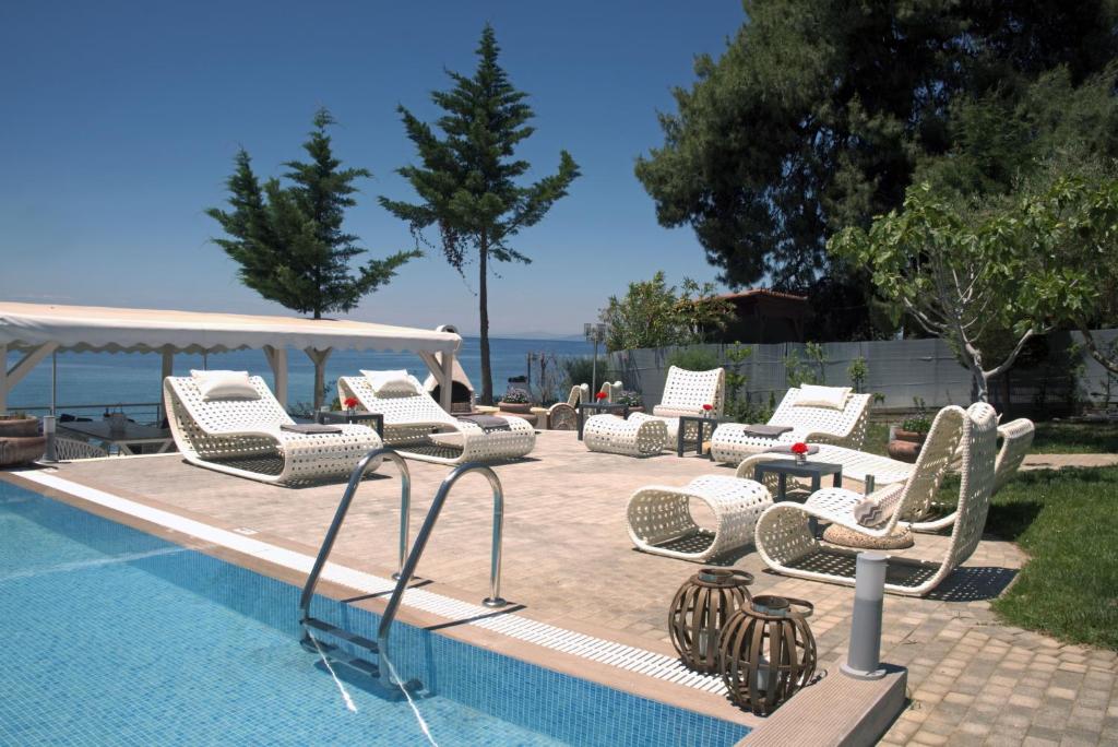a group of chairs and tables next to a swimming pool at Acrotel Athena Villa in Elia