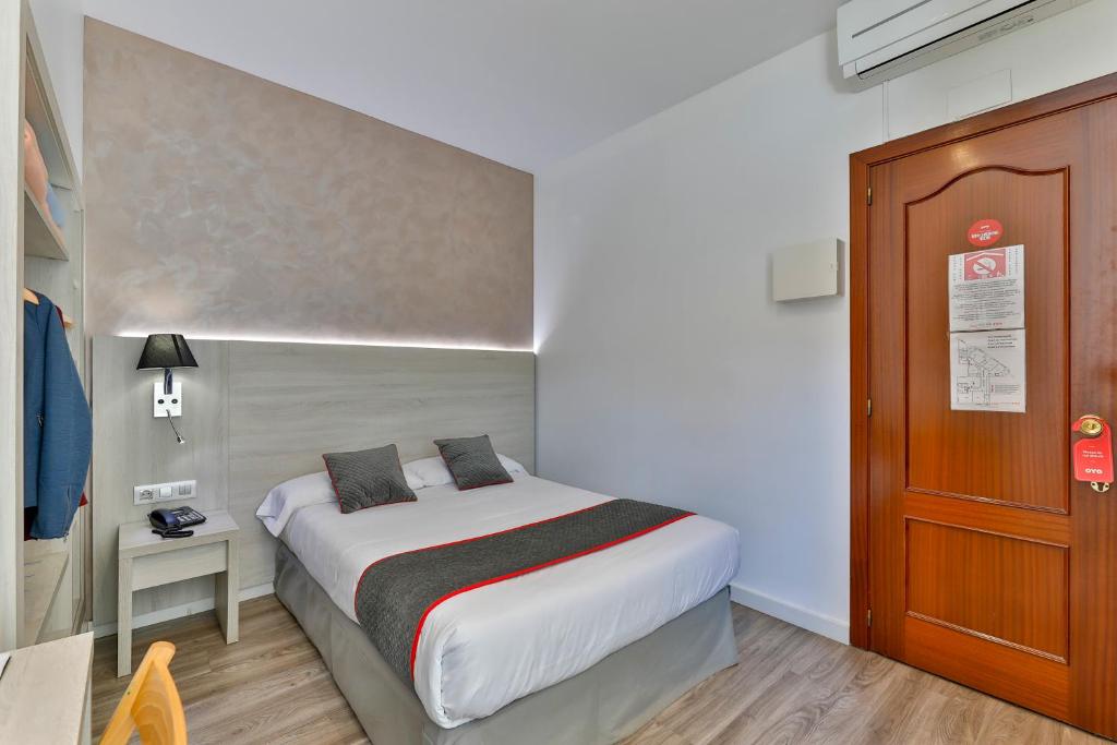 Habitación pequeña con cama y puerta de madera en Hostal Soler en Sant Joan de Vilatorrada