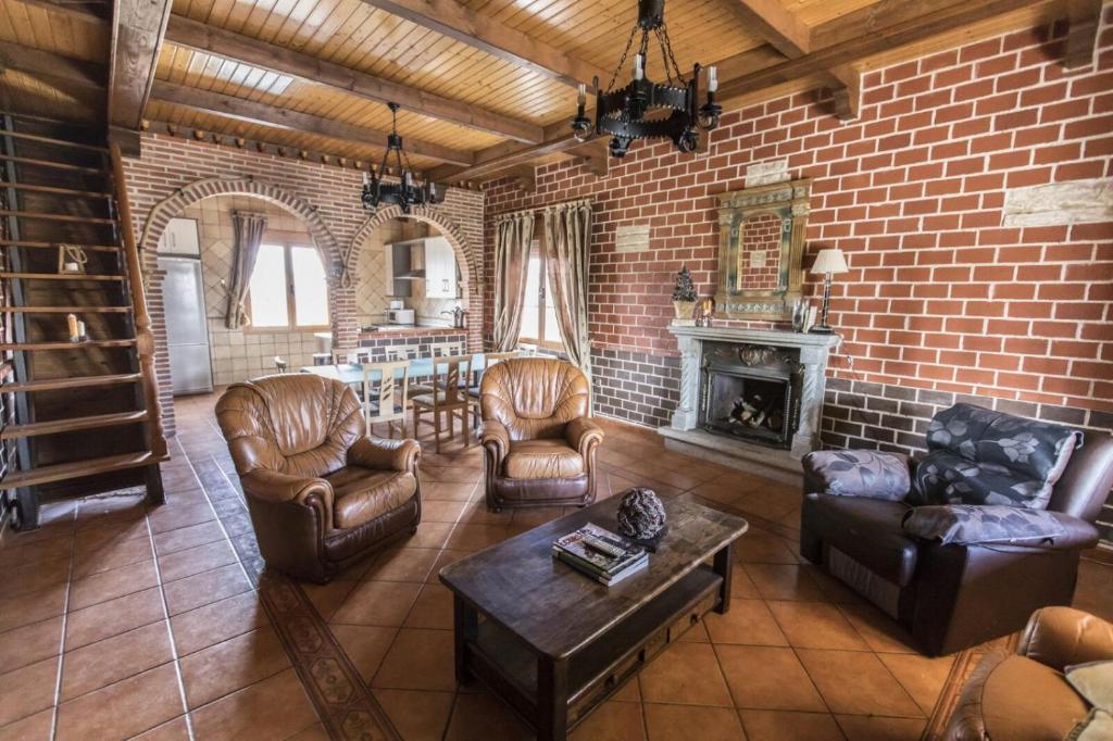 a living room with leather furniture and a brick wall at Casa Rural Rio Agueda in Ciudad-Rodrigo
