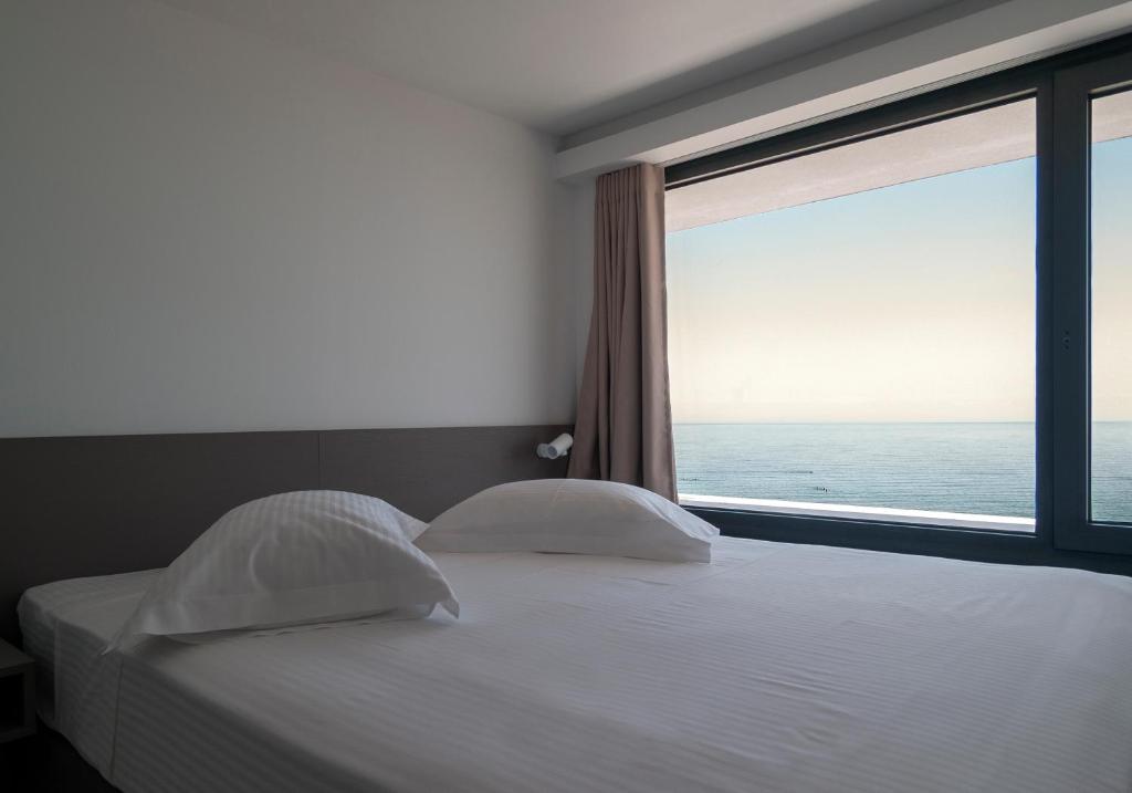 - une chambre avec un lit et une grande fenêtre dans l'établissement Olympos Suites Apartments, à Leptokaryá