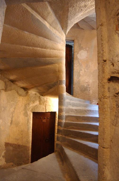 - un escalier dans un ancien bâtiment en pierre avec une porte en bois dans l'établissement La maison des archers, à Saint-Saturnin