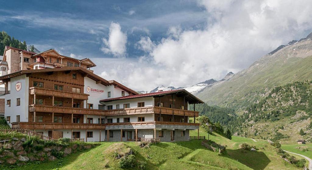 a building on a hill with mountains in the background at Gurglhof Apartmenthaus in Obergurgl