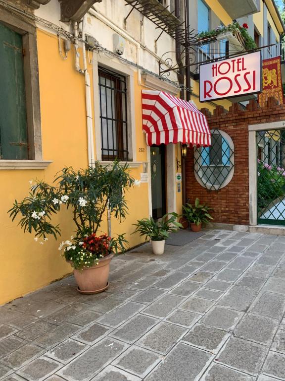 a building with a red and white umbrella and plants at Hotel Rossi in Venice