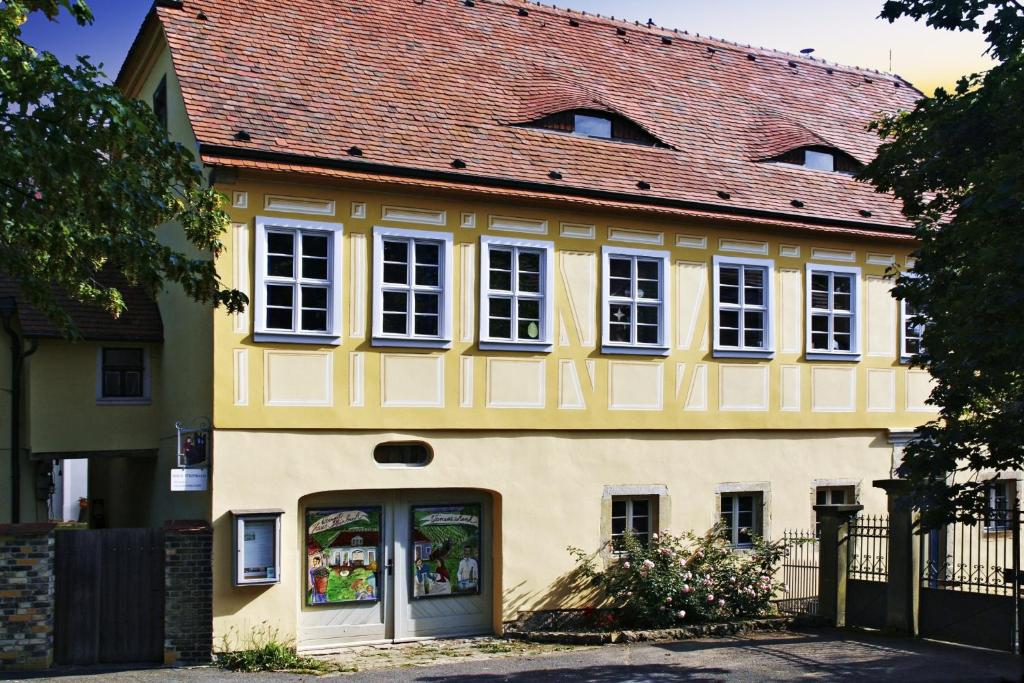 żółty dom z czerwonym dachem w obiekcie Weingut Haus Steinbach w mieście Radebeul
