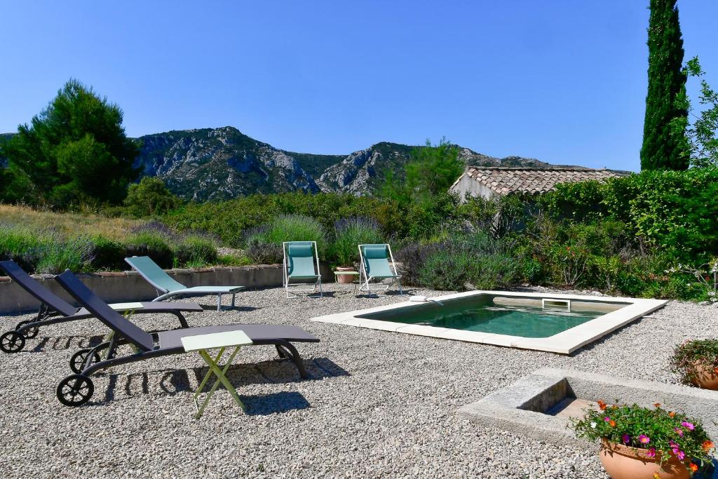een groep stoelen en een zwembad in een tuin bij Le Mas des Genets in Saint-Rémy-de-Provence