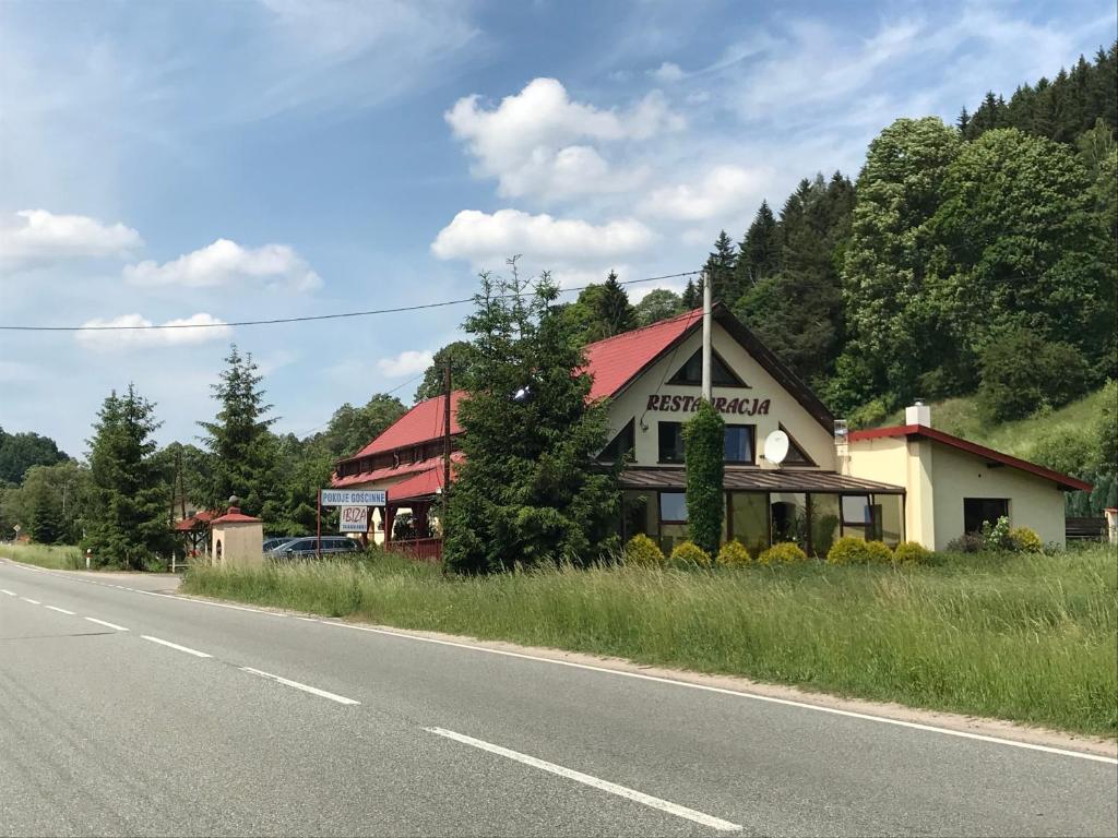 a building with a red roof on the side of a road at Restauracja IBIZA in Ludwikowice Kłodzkie