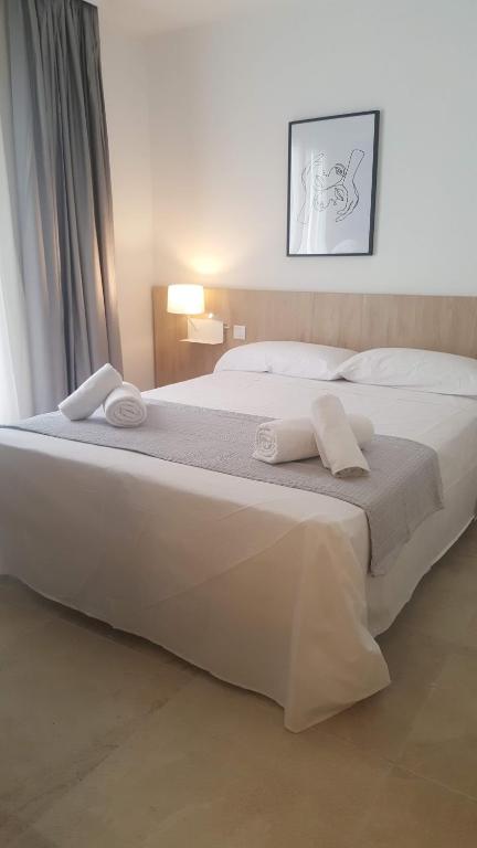 1 cama blanca grande con 2 toallas en Hotel Victori, en Es Castell