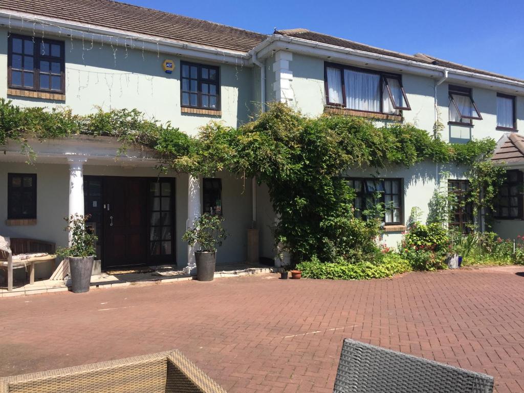 a house with a brick driveway in front of it at Parc Lodge Guesthouse in Bridgend