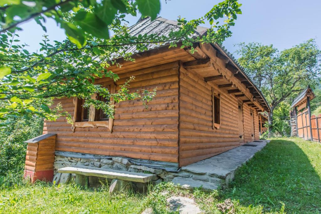 una cabaña de madera con un banco en el césped en Садиба над потоком, en Lumshory