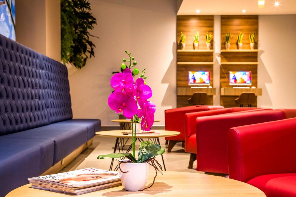 Una sala de espera con un sofá azul y flores rosas. en Hotel Pance 122 Wellness Spa, en Cali