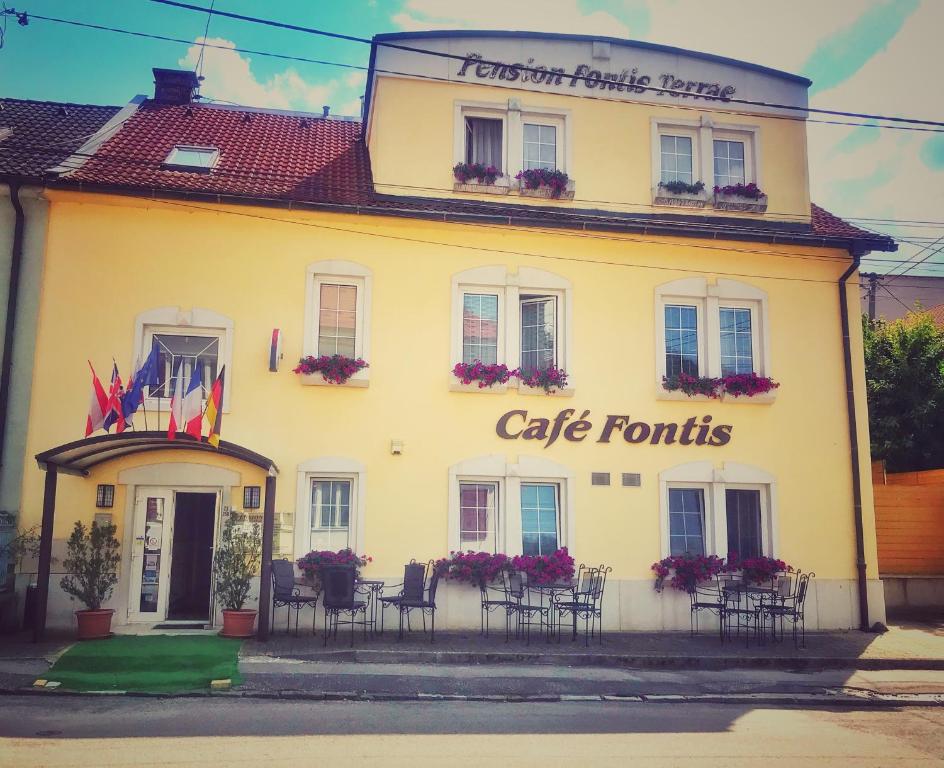 a white building with tables and chairs in front of it at Penzion Fontis Terrae in Trenčianske Teplice