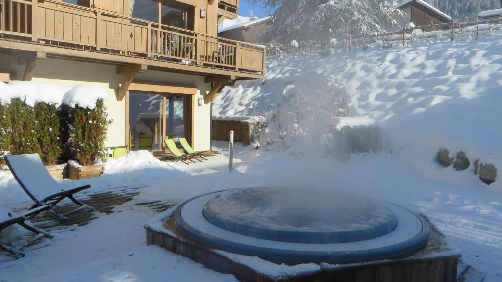 a hot tub in the snow in front of a house at Alpine Lodge 5 in Les Contamines-Montjoie