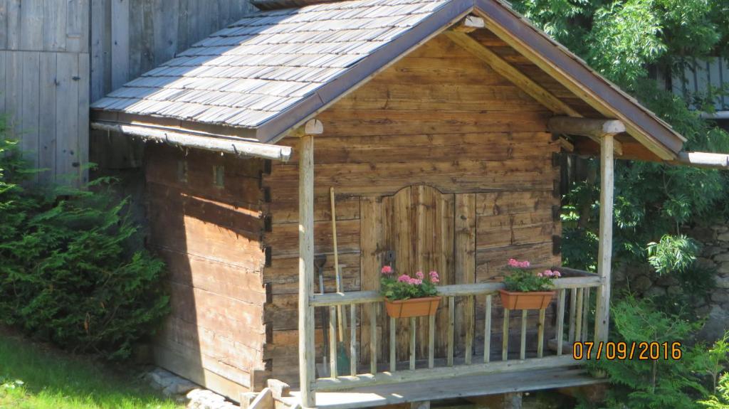 a wooden dog house with a wooden door and flowers at Alpine Lodge 5 in Les Contamines-Montjoie