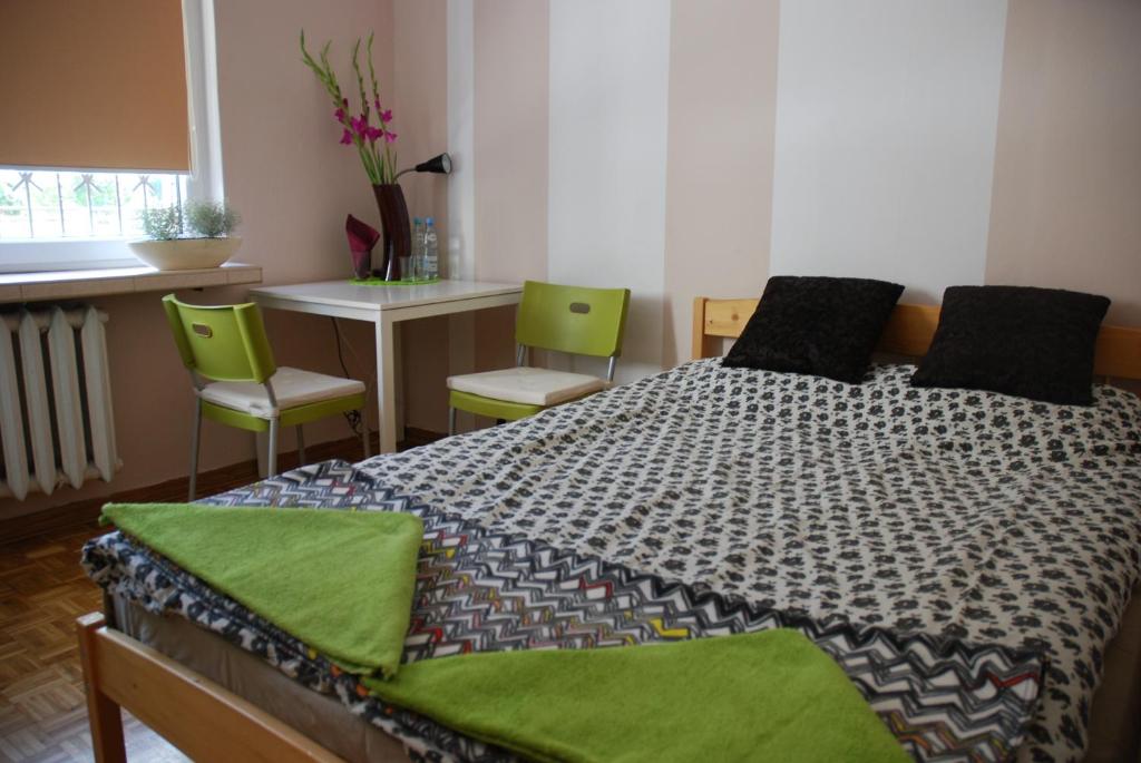 a bedroom with a bed and two green chairs at Lama Rooms in Warsaw