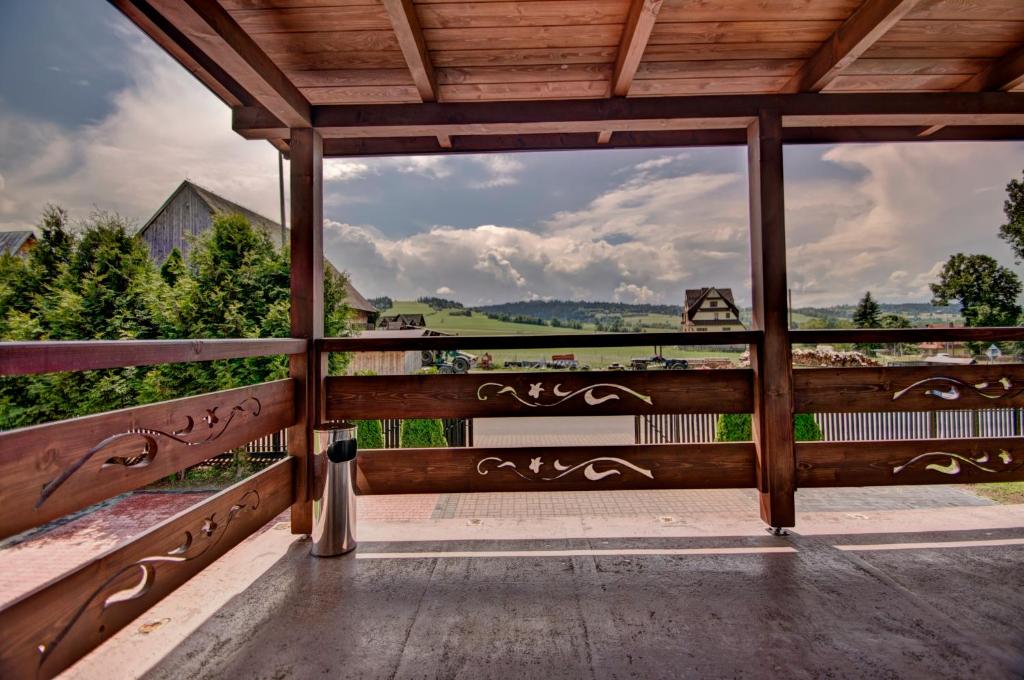 a wooden porch with a view of a field and trees at Dom Na Borku in Ciche