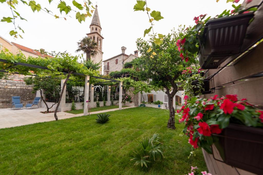 een tuin met rode bloemen en een gebouw bij Apartments Trifunovic Old Town in Budva