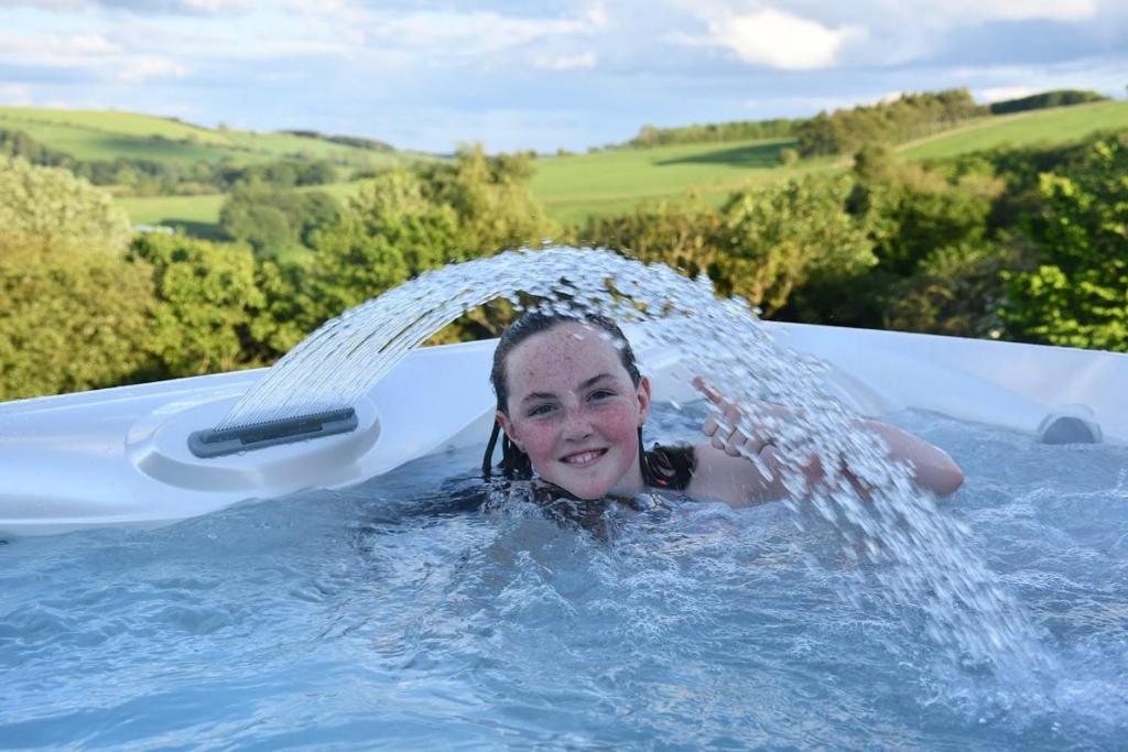 a young girl is splashing in a swimming pool at Long Wood Lodges in Knighton