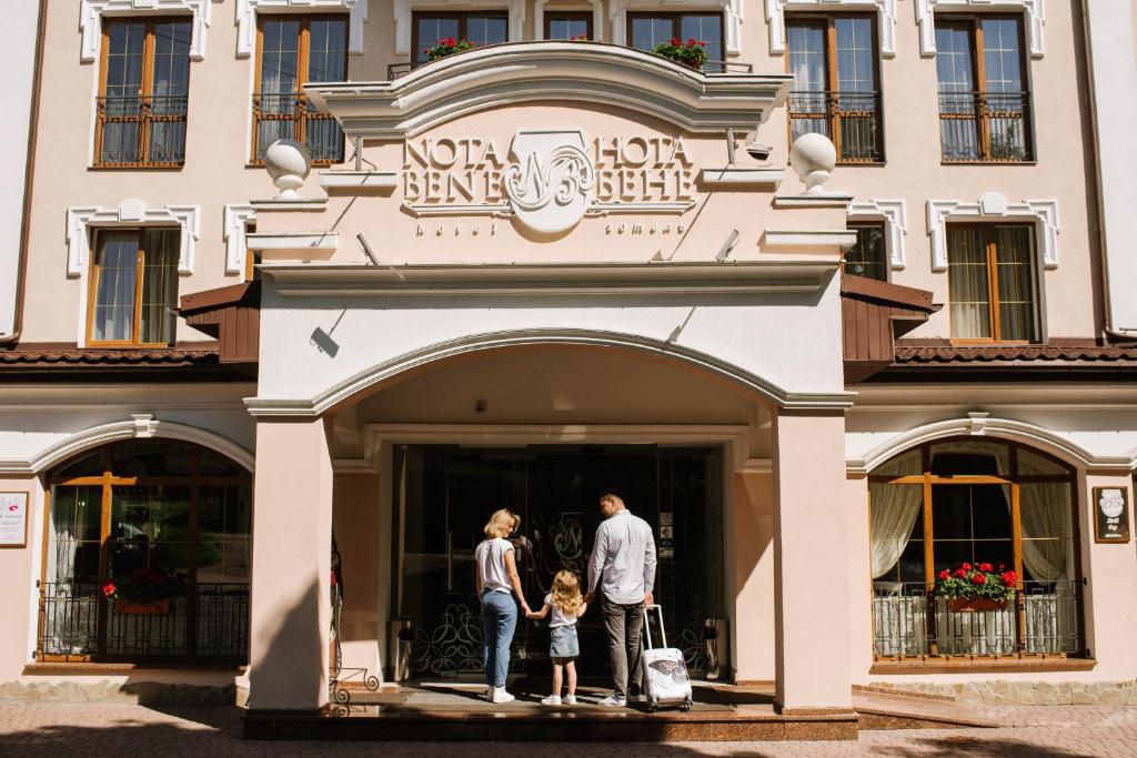 a man and a woman and a child standing in front of a building at Nota Bene Hotel & Restaurant in Lviv