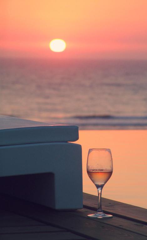 a glass of wine sitting on the beach at sunset at Le Grand Hotel de la Plage in Biscarrosse-Plage