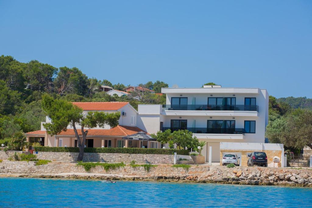 ein Haus am Ufer eines Wasserkörpers in der Unterkunft Hotel Paradise Punta in Nečujam