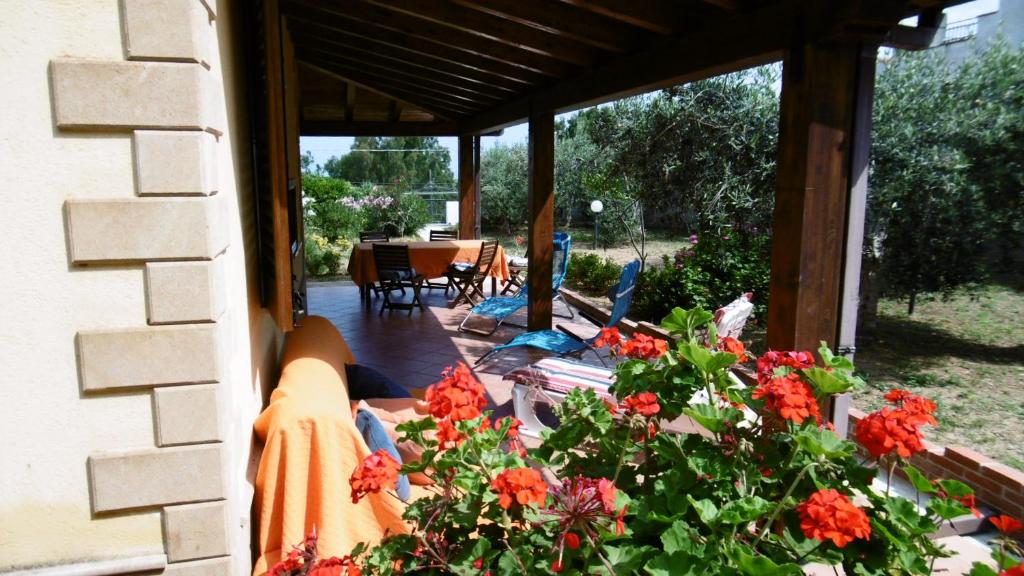 un patio con flores rojas, mesa y sillas en Casa Mare, en Balestrate