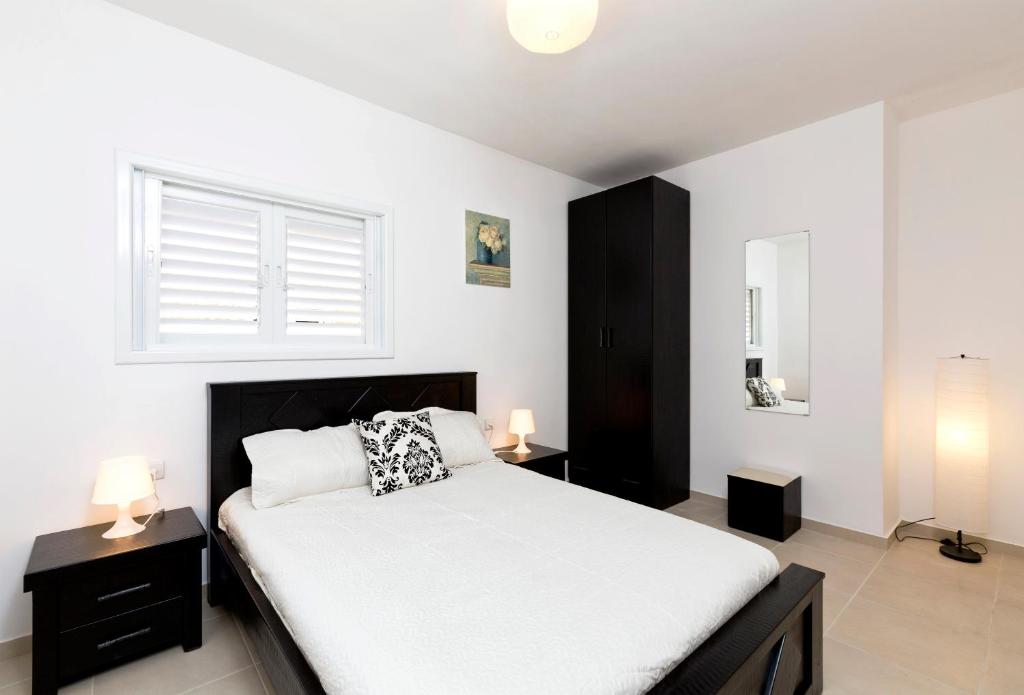 1 dormitorio con 1 cama con sábanas blancas y ventana en Home4Trip Bat Yam, en Bat Yam