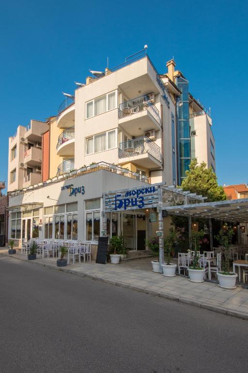 a large building with tables and chairs in front of it at Семеен хотел Бриз in Sozopol