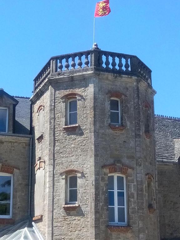 un bâtiment avec un drapeau en haut dans l'établissement chez marîo, à Saint-Pierre-Église