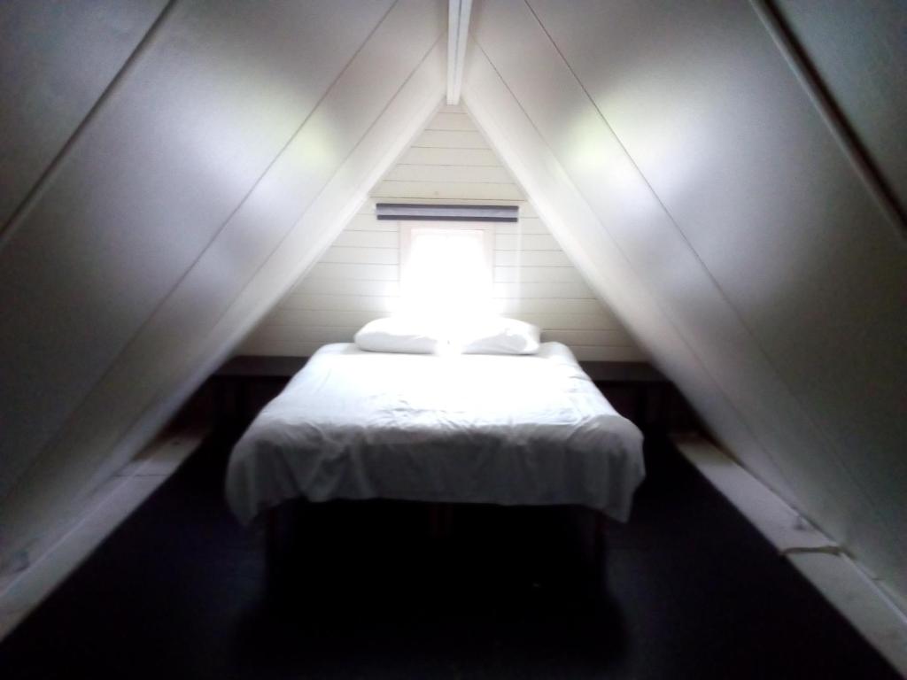 a small bed in a small room with a window at Tinyhouse op Terschelling in Hoorn