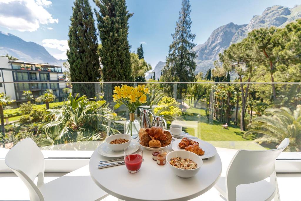 uma mesa branca com comida numa varanda com montanhas em Du Lac Et Du Parc Grand Resort em Riva del Garda