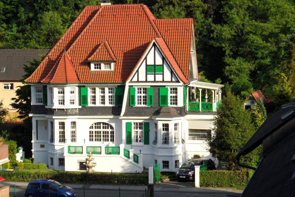 Casa blanca grande con techo rojo y persianas verdes en Villa Biso, en Solingen