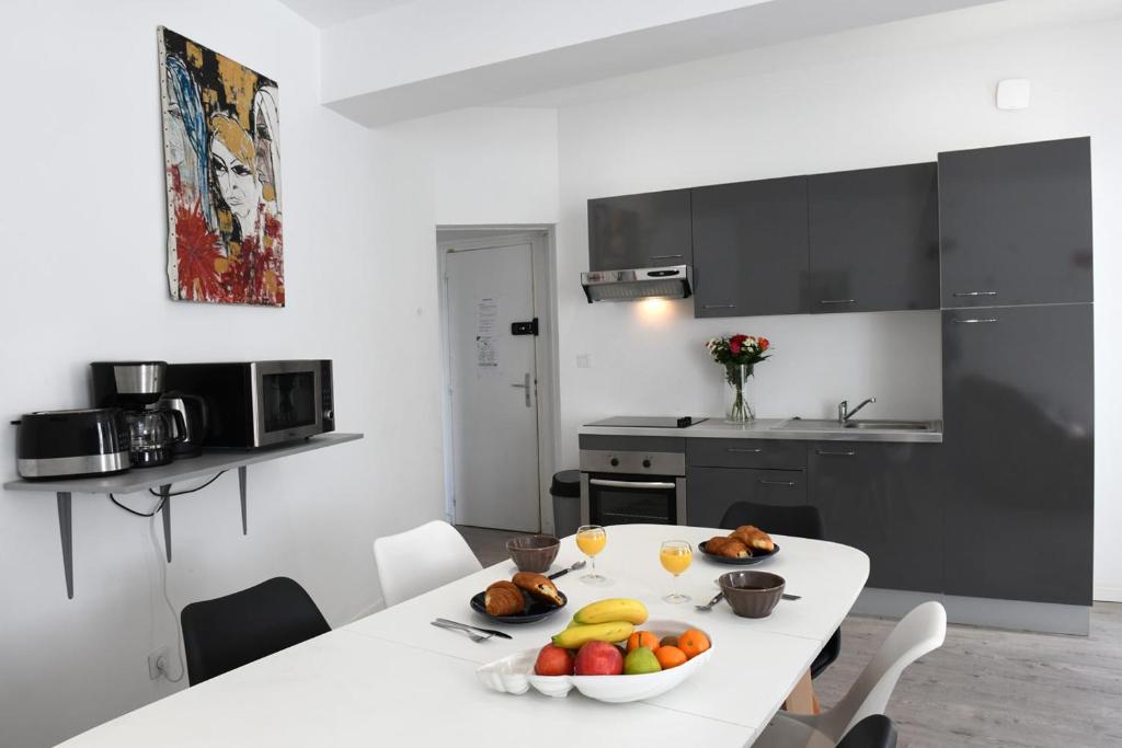 a kitchen with a white table with a bowl of fruit on it at La Grande Marée in Dieppe