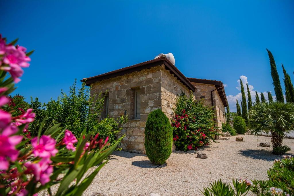 einen Garten mit einem Steinhaus und ein paar Blumen in der Unterkunft Gujadani Villa in Simou