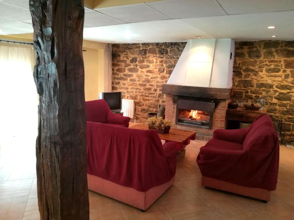 a living room with two red chairs and a fireplace at Casa Rural Barracas in Barracas