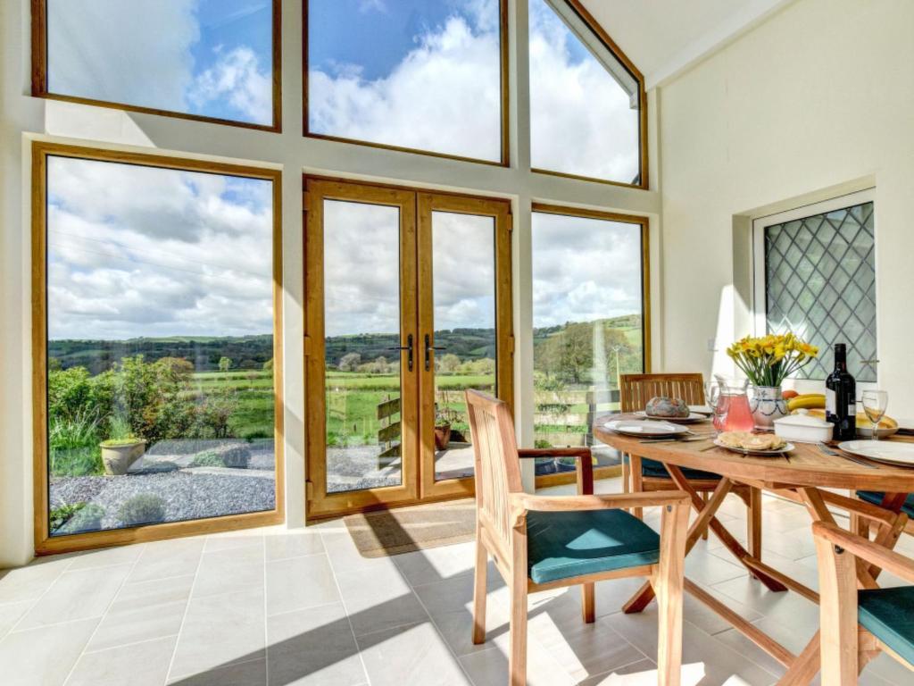 a dining room with a table and chairs and large windows at Holiday Home Nythfa by Interhome in Llanycrwys