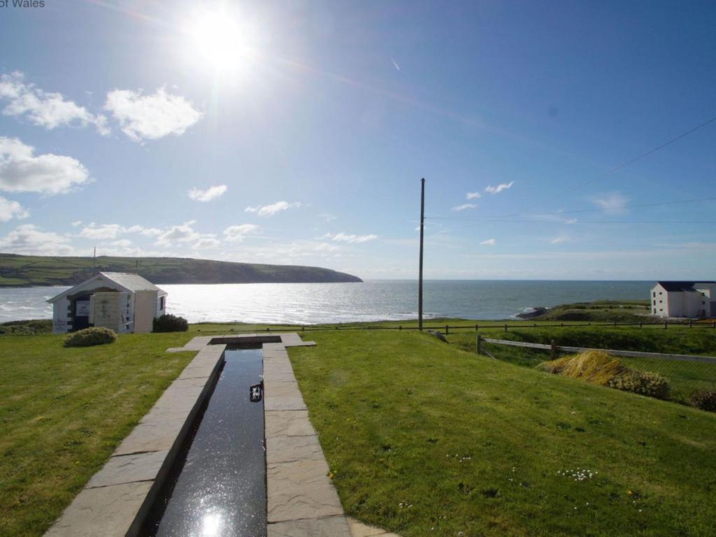 a walkway next to the ocean with the sun in the sky at Holiday Home Tully Hip by Interhome in Towyn