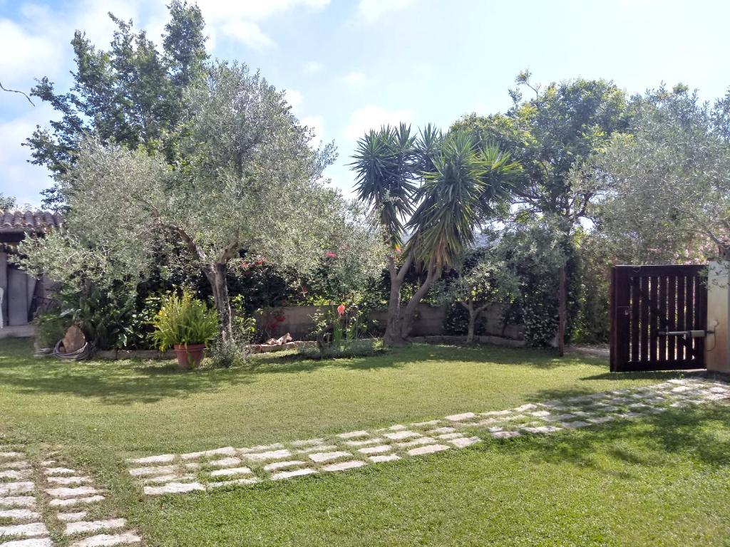 un cortile con cancello, alberi e erba di Villa Pontes a Marina di Orosei