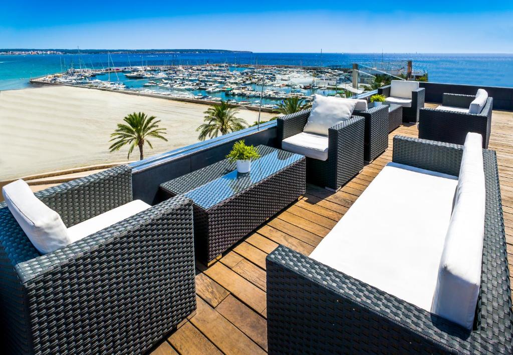 een balkon met rieten stoelen en uitzicht op het strand bij Nautic Hotel & Spa in Can Pastilla