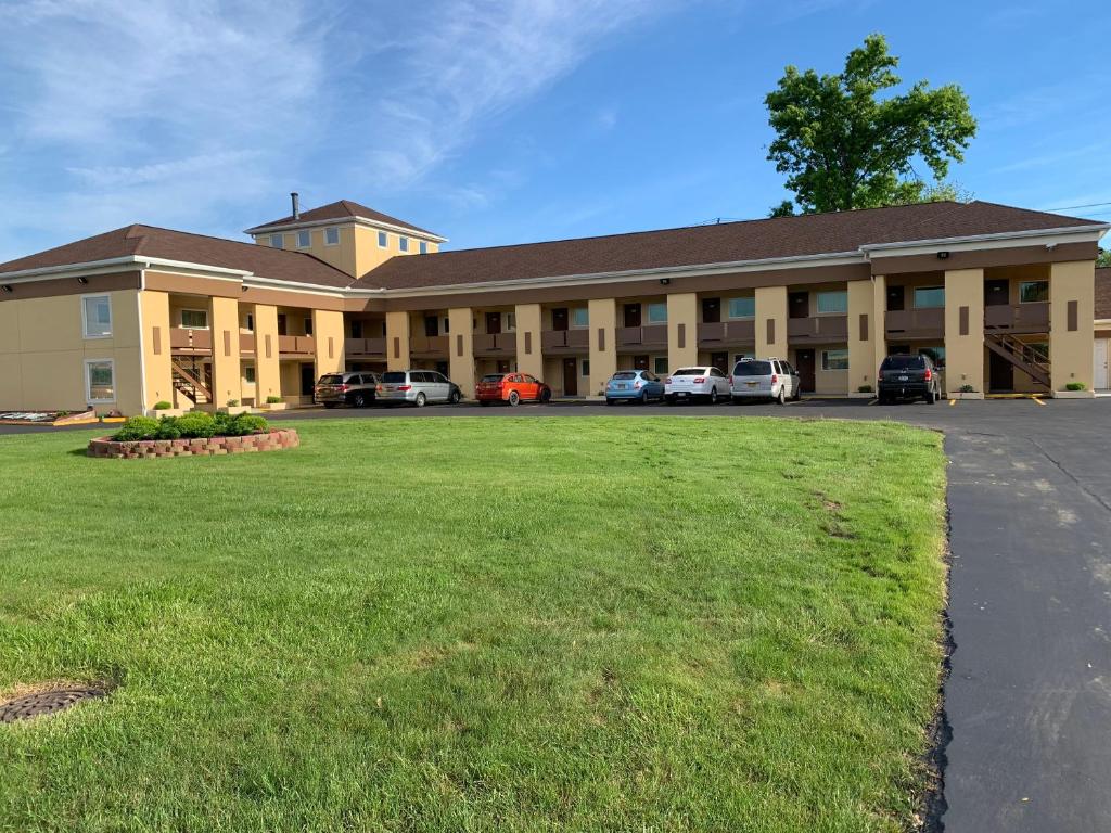 ein großes Gebäude mit Autos auf einem Parkplatz in der Unterkunft Scottish Inns Tonawanda in Tonawanda