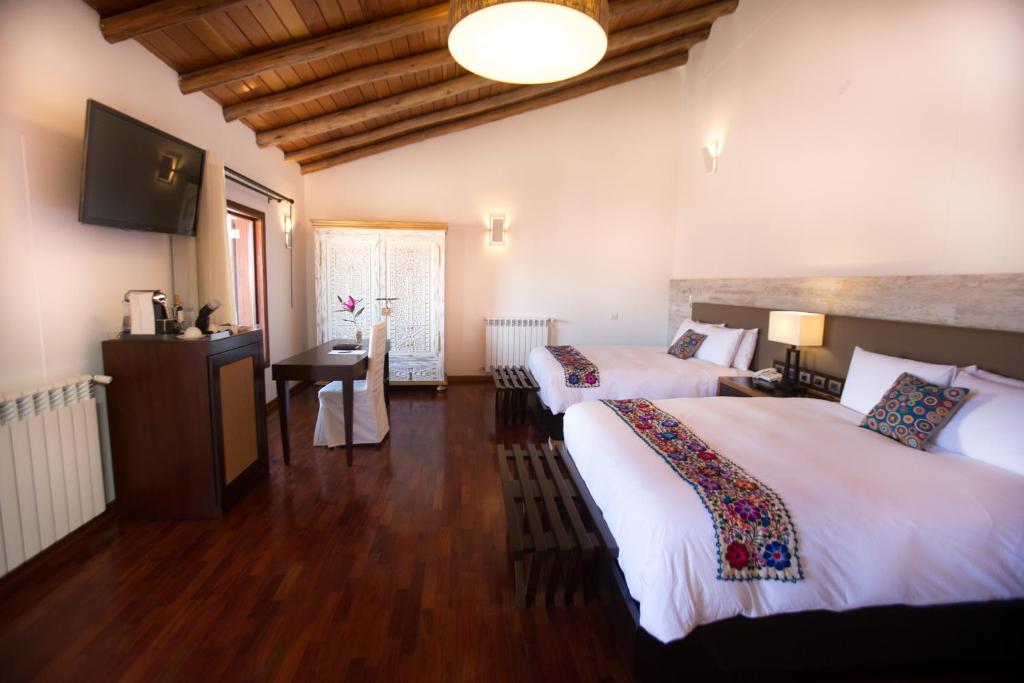 Cette chambre comprend deux lits et une télévision. dans l'établissement Tocuyeros Boutique Hotel, à Cusco
