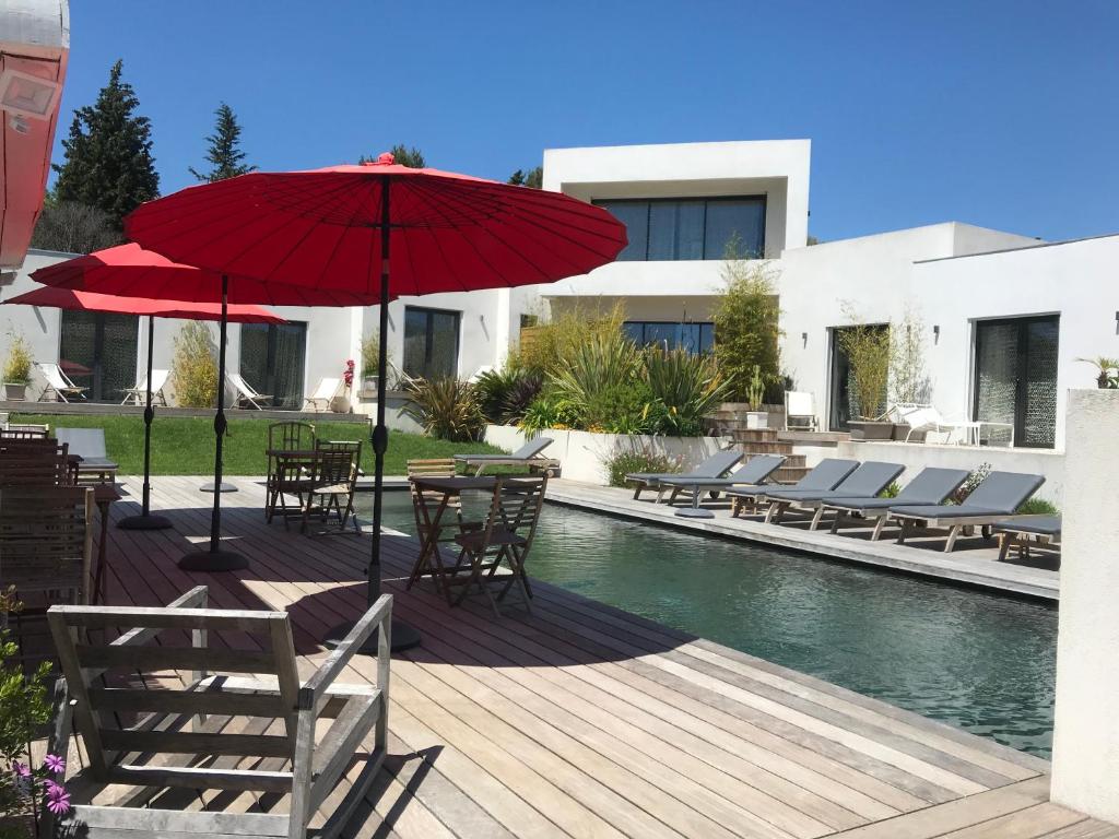 カシにあるVilla le sud appartementsのプールサイドのパティオ(椅子、パラソル付)