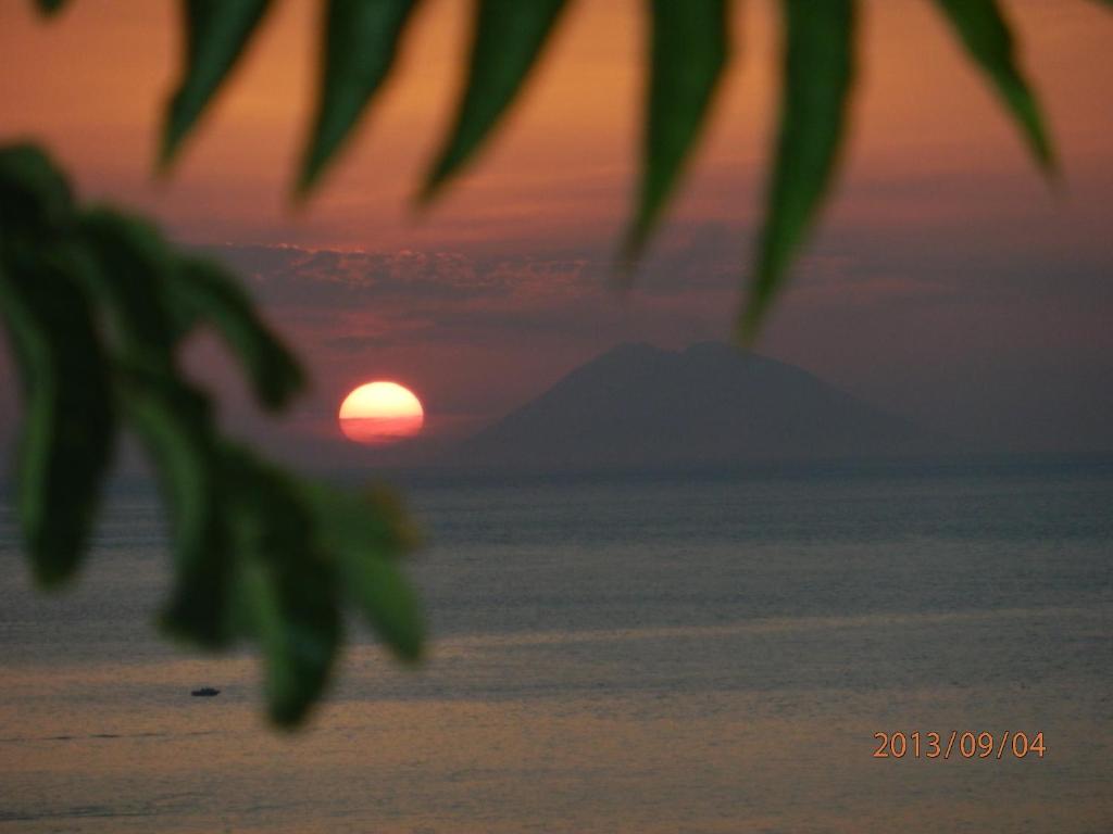 een zonsondergang over de oceaan met een berg op de achtergrond bij Casa vacanze Mare in Parghelia