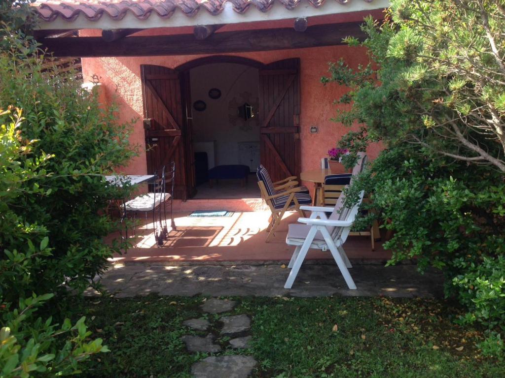un patio con sedie e tavolo di fronte a una casa di Il Melograno Cannigione Villaggio Gallura a Cannigione