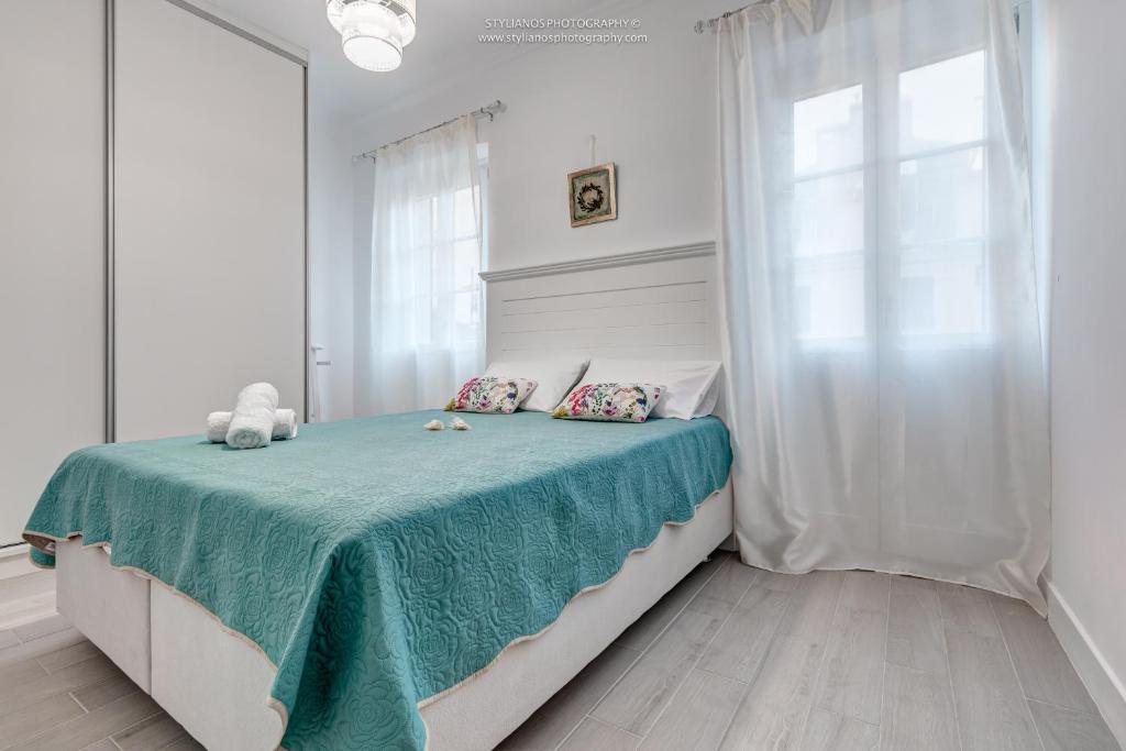 a bedroom with a bed with a green blanket and a window at Celestia Corfu in Corfu